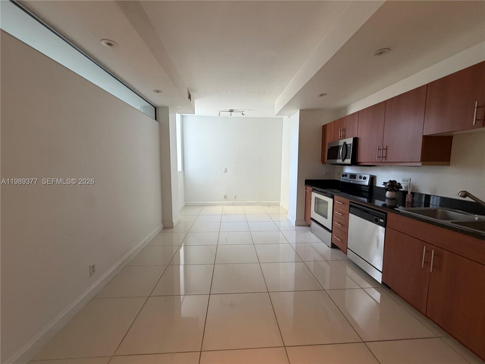 111 East Flagler Street, Unit 606 Miami, FL 33131 - Photo 2 of 10 a large kitchen with stainless steel appliances granite countertop a stove a sink and a microwave