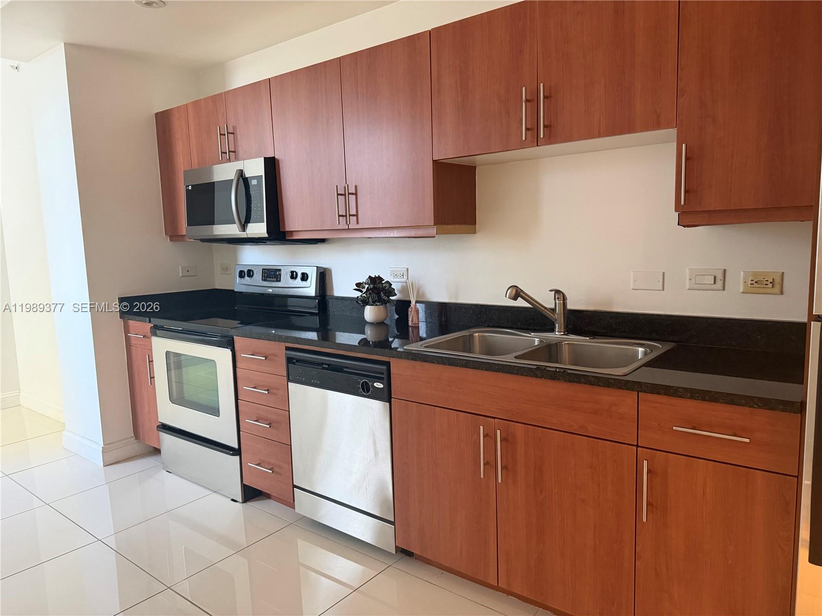 111 East Flagler Street, Unit 606 Miami, FL 33131 - Photo 3 of 10 a kitchen with stainless steel appliances granite countertop a sink stove and microwave