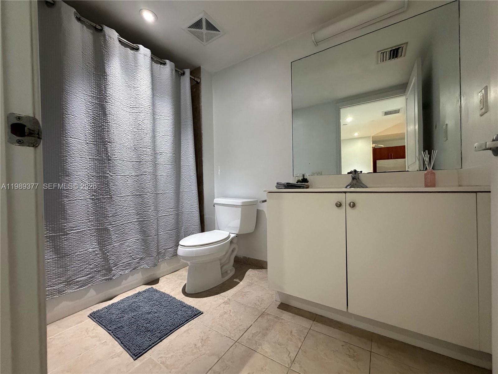 111 East Flagler Street, Unit 606 Miami, FL 33131 - Photo 8 of 10 a bathroom with a sink a toilet a mirror and shower