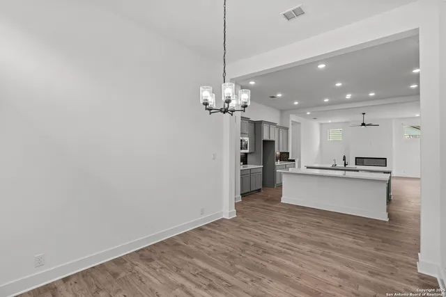 a large kitchen with stainless steel appliances lots of counter space a sink and a stove top oven with wooden floor