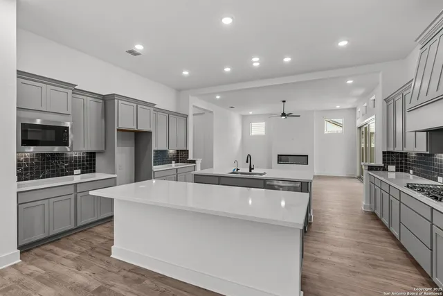 a large white kitchen with kitchen island a sink a stove a center island a stove and cabinets