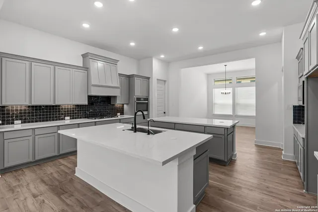 a large kitchen with stainless steel appliances granite countertop a large counter top a stove a refrigerator cabinets and living room view