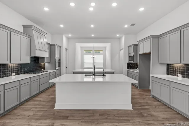 a large kitchen with stainless steel appliances kitchen island granite countertop a stove and a sink