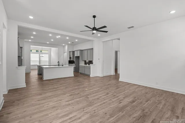 a view of an empty room with a window and wooden floor