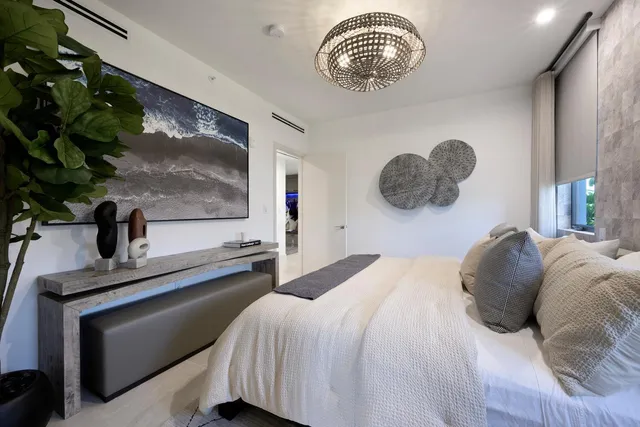 a bedroom with a bed and a potted plant on the dresser