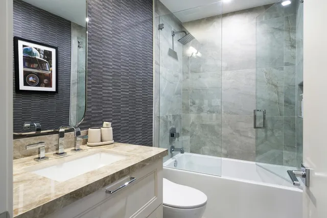 a bathroom with a granite countertop sink a toilet and bathtub