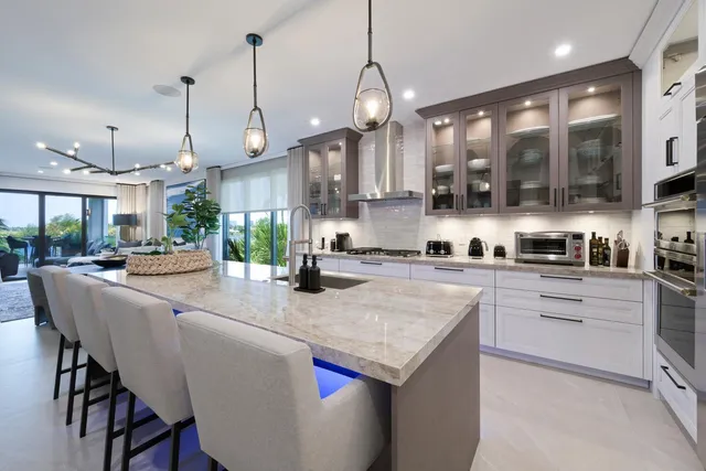 a kitchen with stainless steel appliances granite countertop a stove a sink a oven a kitchen island with white cabinets and wooden floor