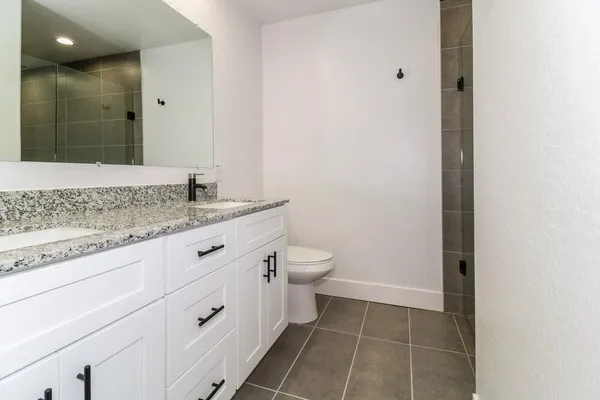 a bathroom with a granite countertop sink a toilet and a mirror