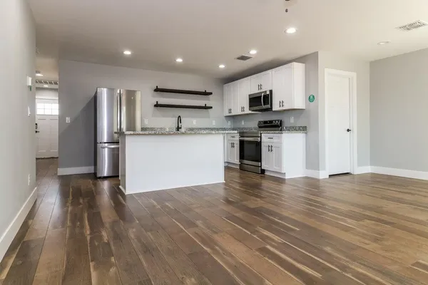 a kitchen with stainless steel appliances granite countertop a refrigerator oven a sink dishwasher and a stove with wooden floor
