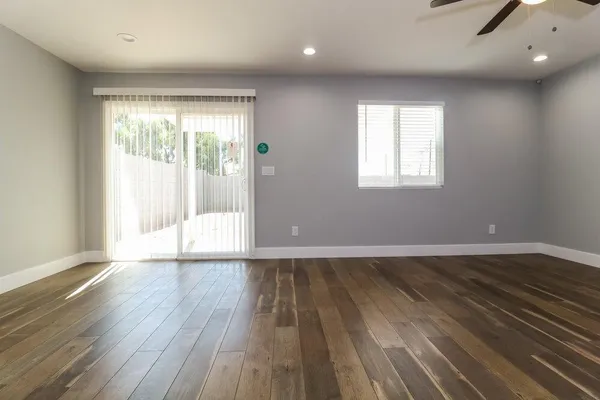 an empty room with wooden floor and windows