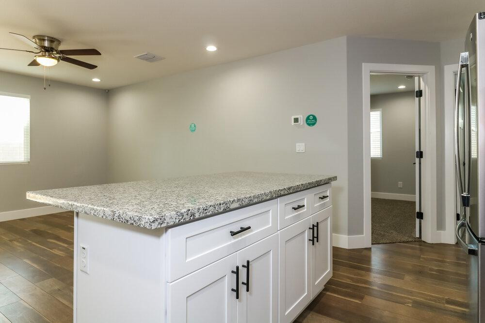 3865 West Gaby Road Phoenix, AZ 85041 - Photo 7 of 16 a kitchen with granite countertop a sink and a refrigerator