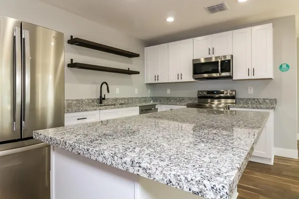 a kitchen with stainless steel appliances granite countertop a sink stove and refrigerator