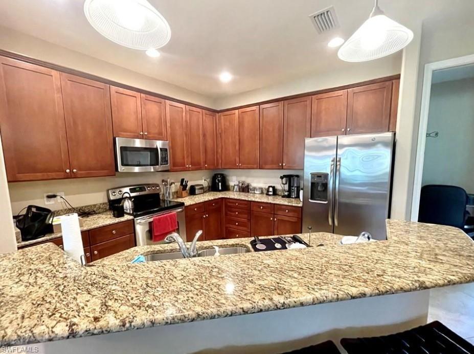 9050 Capistrano Street North, Unit 4102 Naples, FL 34113 - Photo 6 of 31 a kitchen with granite countertop wooden cabinets a stove top oven a sink and dishwasher
