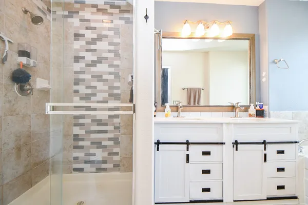 a bathroom with a double vanity sink mirror and shower