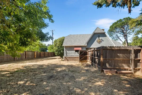 a view of a house with a small yard plants and large tree