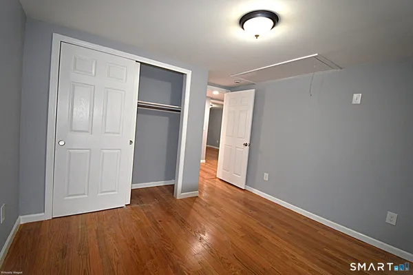 a view of an empty room with wooden floor and closet