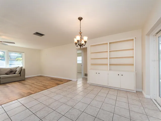 a view of a livingroom with a chandelier fan and windows