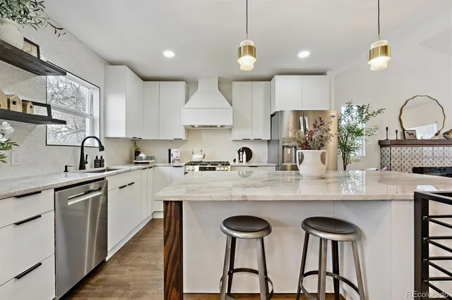 a kitchen with stainless steel appliances granite countertop a sink a stove a refrigerator cabinets and chairs