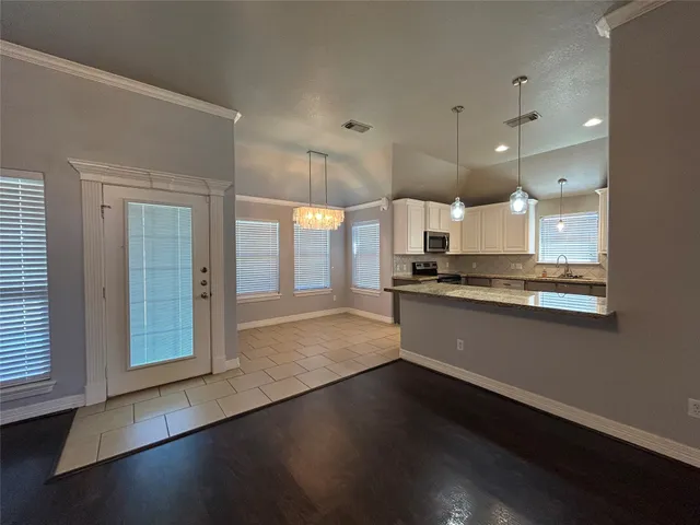 a view of a kitchen with a sink and dishwasher a stove top oven with wooden floor