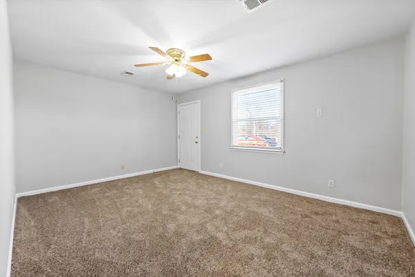 an empty room with windows and fan