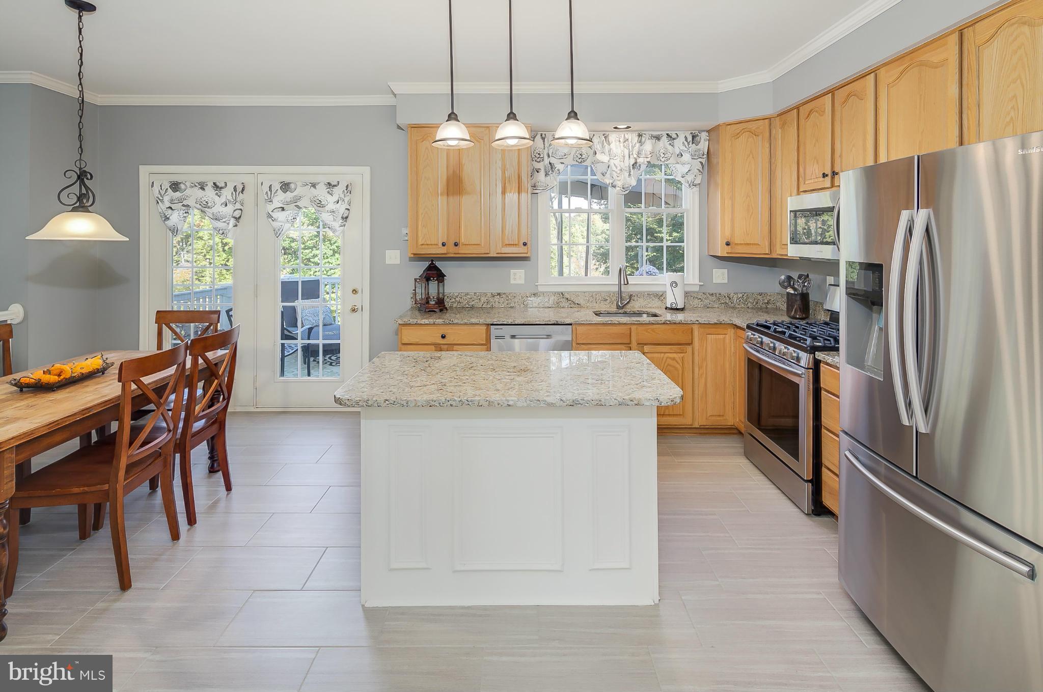 5949 Sandy Ridge Elkridge, MD 21075 - Photo 7 of 30 a kitchen with stainless steel appliances granite countertop a refrigerator a sink a stove and island