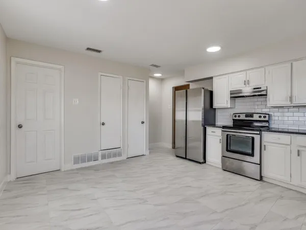 a kitchen with granite countertop a refrigerator and a stove top oven