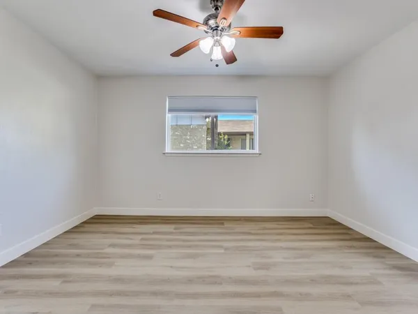 a view of an empty room with window and a chandelier fan
