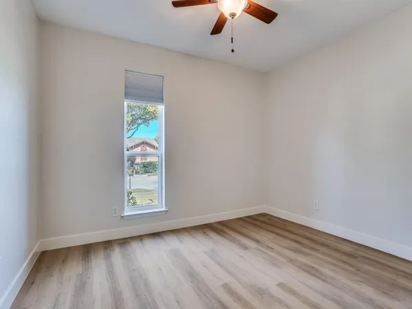 an empty room with a window and a ceiling fan
