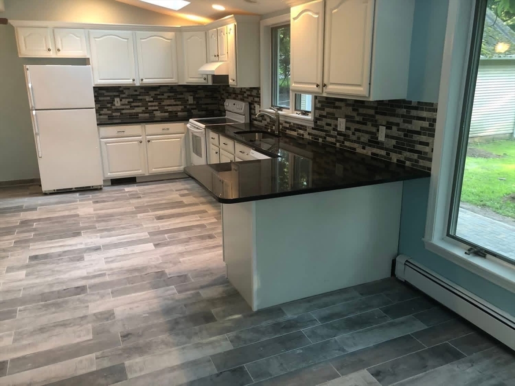 63 River Street, Unit 1 Middleton, MA 01949 - Photo 6 of 19 a kitchen with granite countertop a sink and a stove top oven