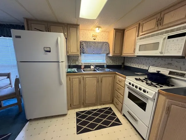 a white refrigerator freezer and a stove sitting inside of a kitchen