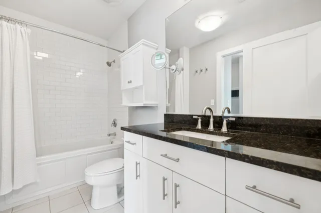 a bathroom with a granite countertop sink a toilet a mirror and shower