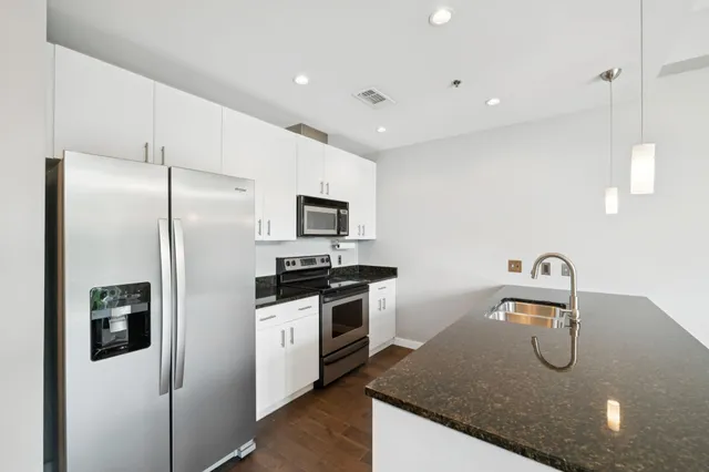 a kitchen with stainless steel appliances granite countertop a sink a stove and refrigerator