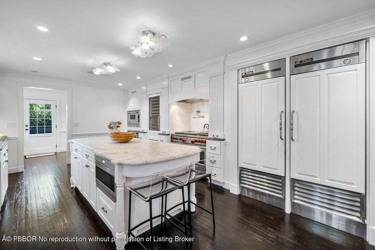 100 Regents Park Road Palm Beach, FL 33480 - Photo 12 of 42 a kitchen with a table chairs refrigerator and wooden floor