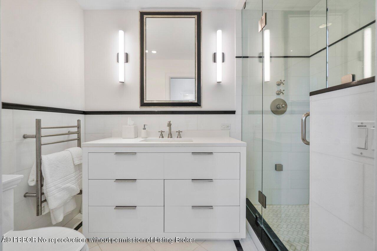 100 Regents Park Road Palm Beach, FL 33480 - Photo 18 of 42 a bathroom with a sink a mirror and shower