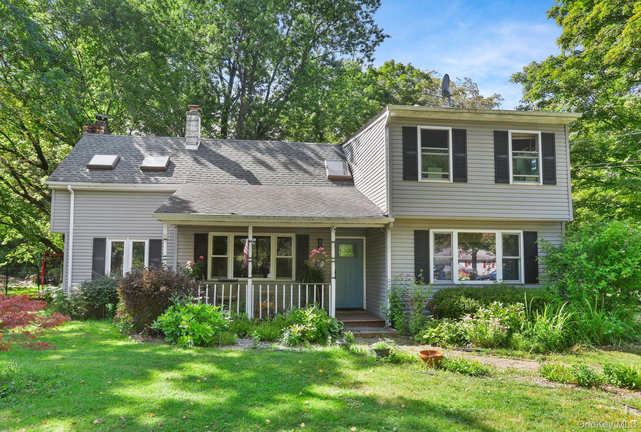 View of front of house featuring a porch, a chimney, a front lawn, and roof with shingles