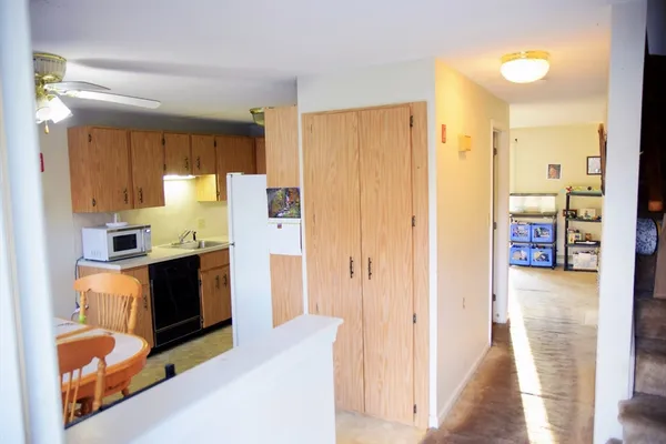 a living room with stainless steel appliances furniture a fireplace and a kitchen view