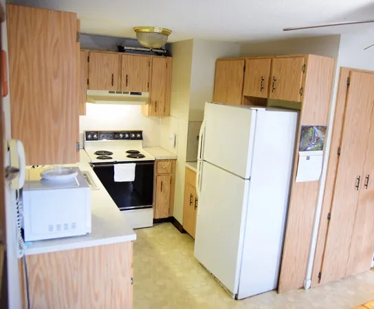 a kitchen with a refrigerator a stove top oven and cabinets