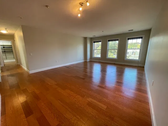 an empty room with wooden floor and windows