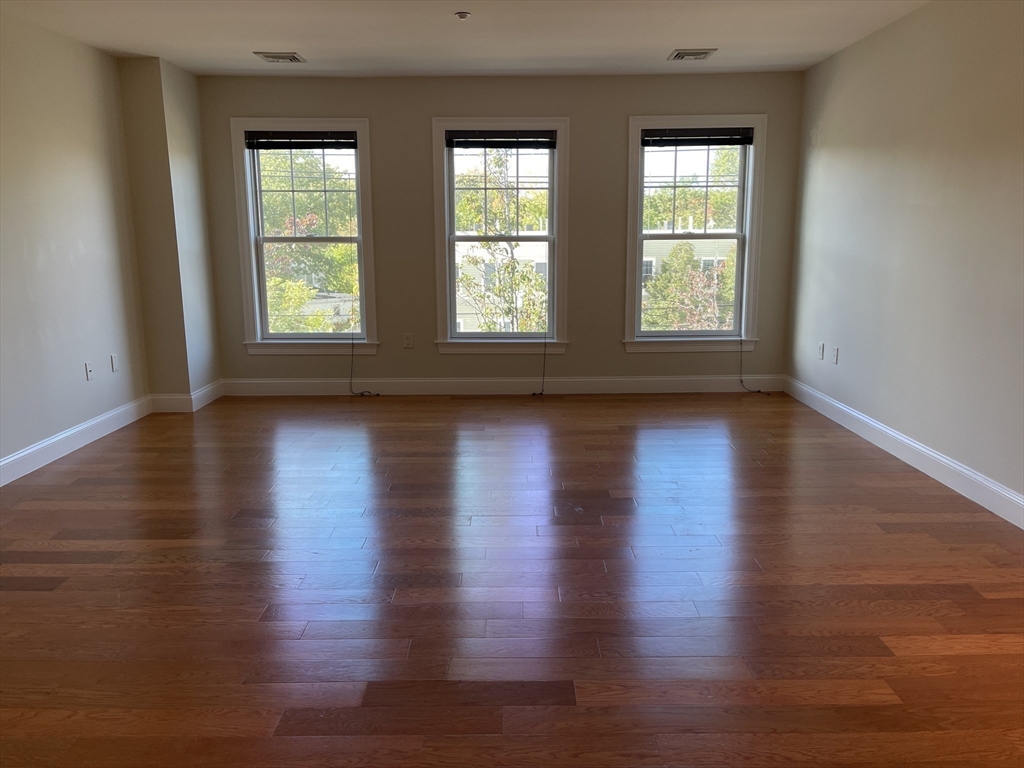 5170 Washington Street, Unit 3 Boston, MA 02132 - Photo 14 of 42 an empty room with wooden floor and windows