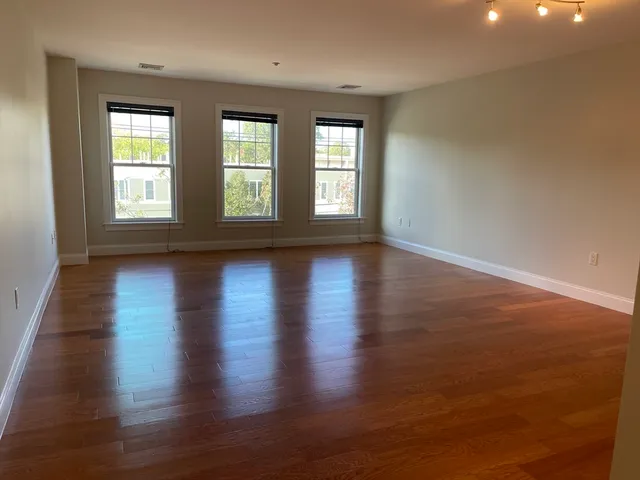 a view of a hallway with wooden floor and a bathroom