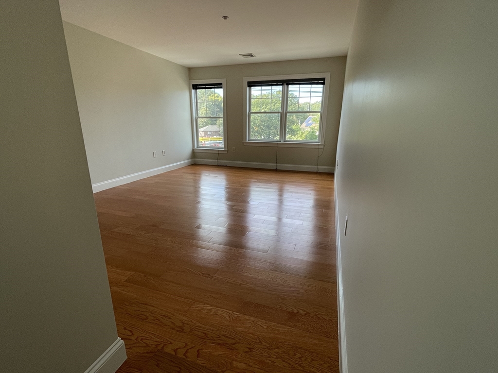 5170 Washington Street, Unit 3 Boston, MA 02132 - Photo 26 of 42 an empty room with wooden floor and windows