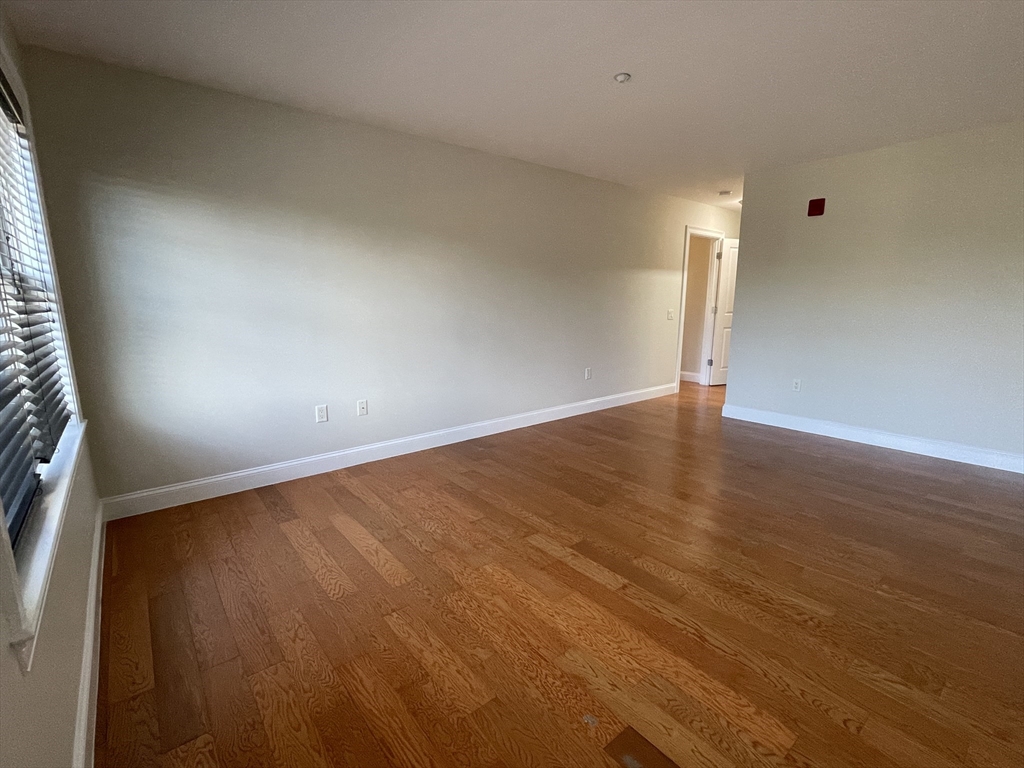 5170 Washington Street, Unit 3 Boston, MA 02132 - Photo 28 of 42 an empty room with wooden floor and windows