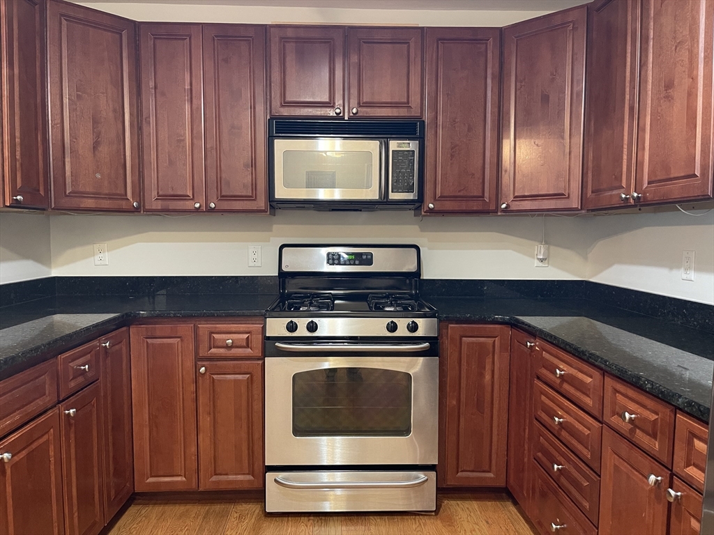 5170 Washington Street, Unit 3 Boston, MA 02132 - Photo 8 of 42 a kitchen with granite countertop wood cabinets and stainless steel appliances