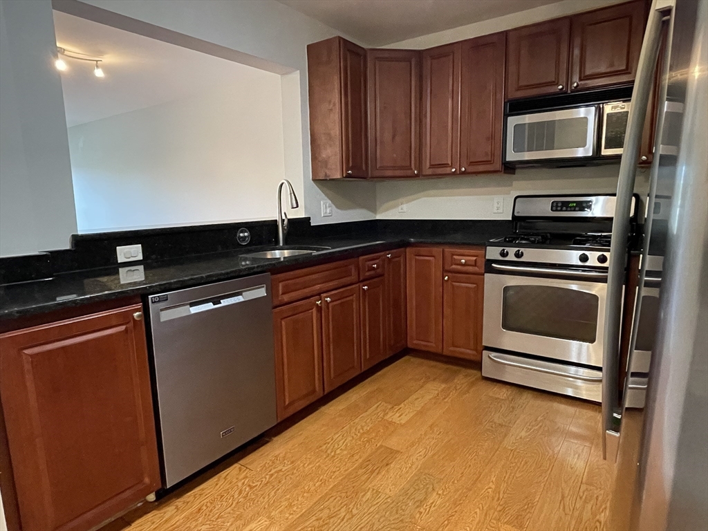 5170 Washington Street, Unit 3 Boston, MA 02132 - Photo 9 of 42 a kitchen with granite countertop a stove top oven microwave and cabinets