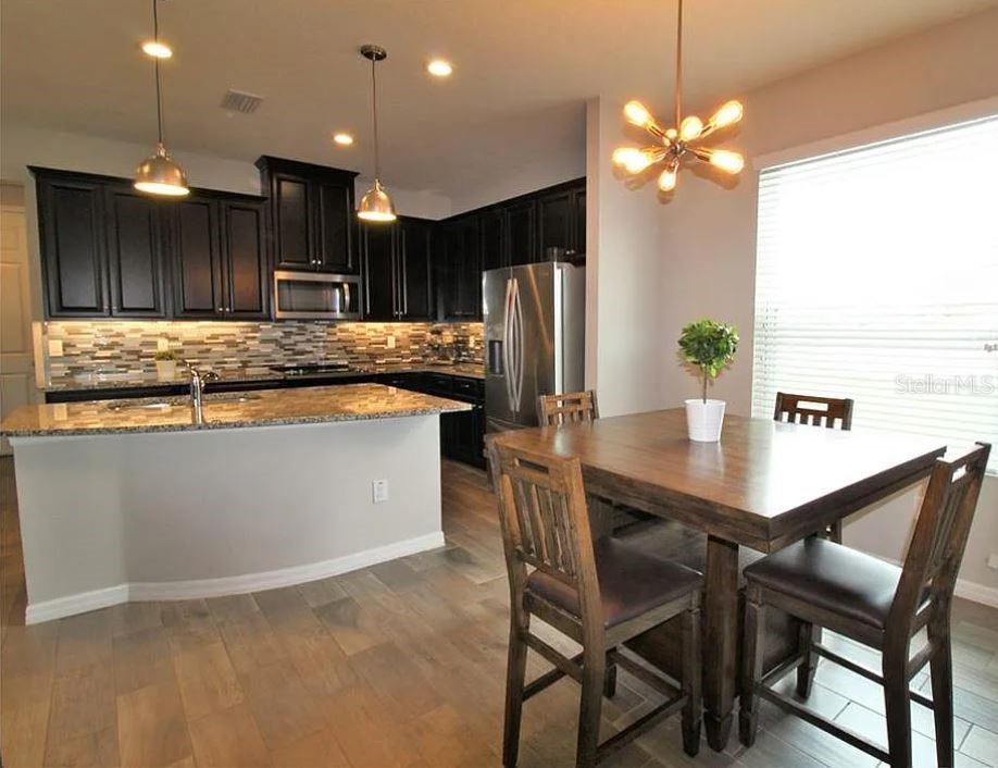 1049 Multiflora Loop Lutz, FL 33558 - Photo 18 of 49 a kitchen with stainless steel appliances kitchen island granite countertop a table chairs and a refrigerator