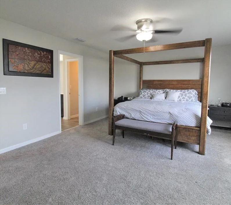 1049 Multiflora Loop Lutz, FL 33558 - Photo 32 of 49 a bedroom with a bed and a chandelier