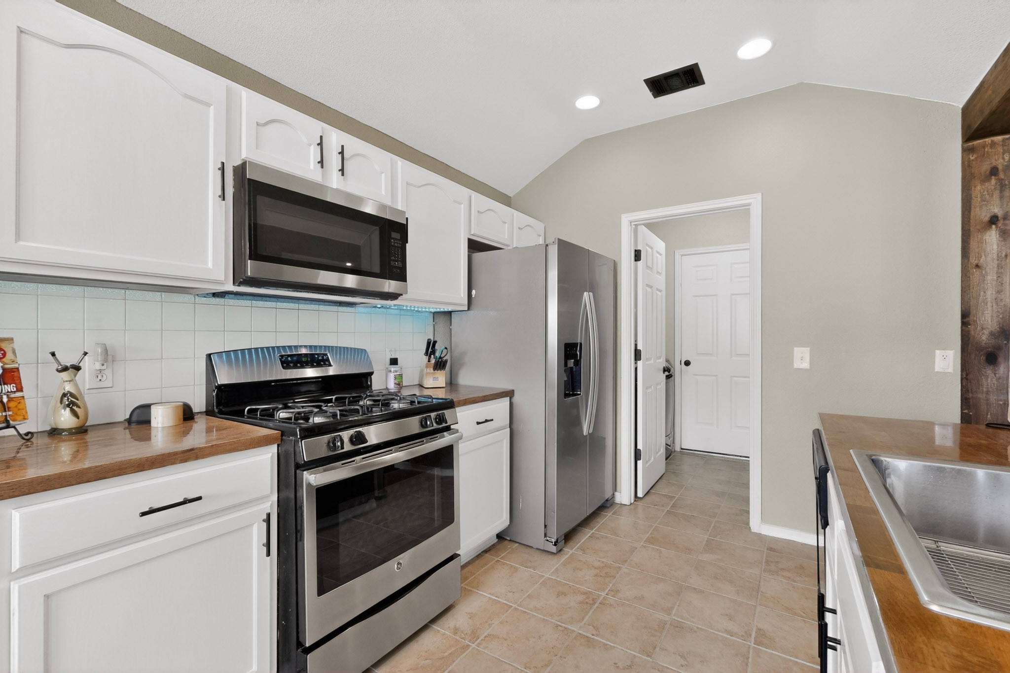 15104 Mimebark Way Austin, TX 78724 - Photo 14 of 38 Kitchen featuring white cabinetry, stainless steel appliances, and a tile backsplash