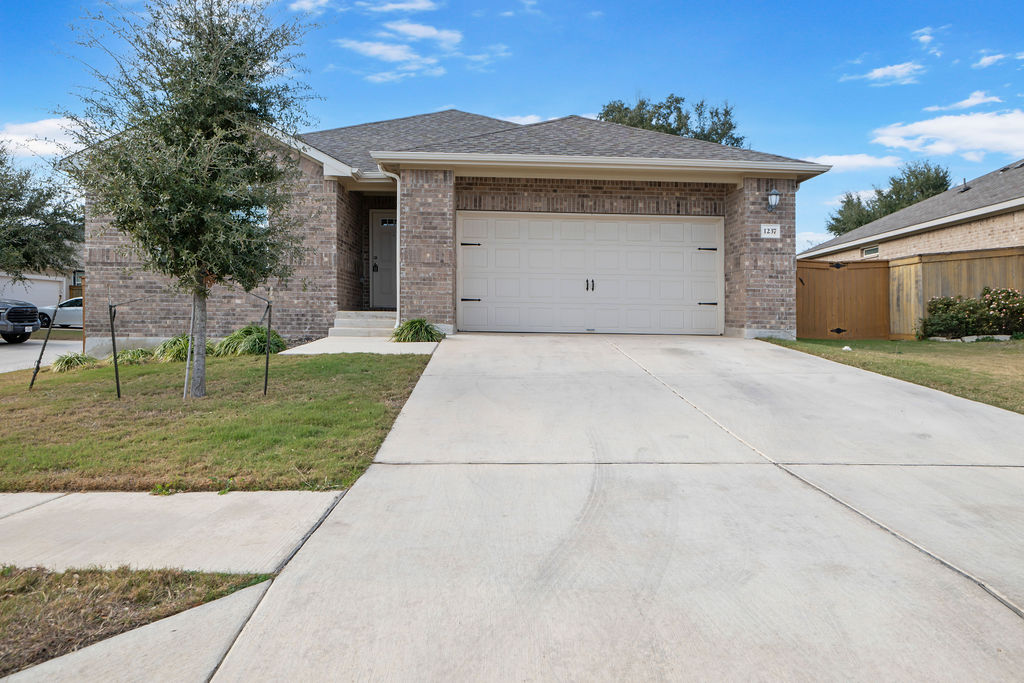 Single story home featuring brick siding, concrete driveway, a shingled roof, and a garage