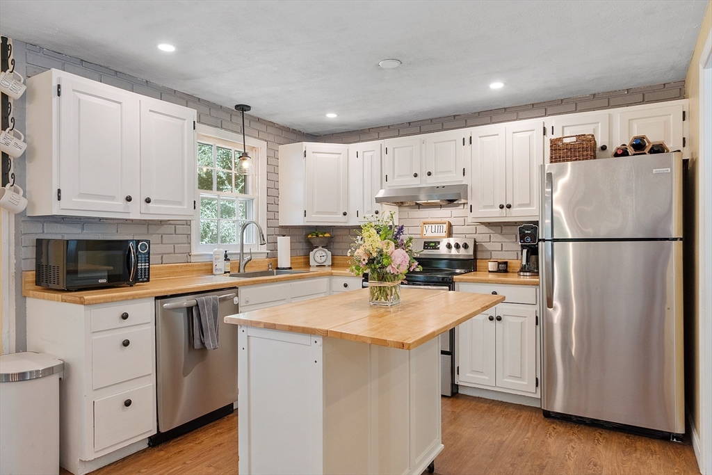14 Emery Road Townsend, MA 01469 - Photo 11 of 31 a kitchen with refrigerator a stove a sink and white cabinets with wooden floor
