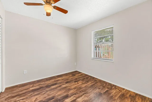 an empty room with a window and ceiling fan